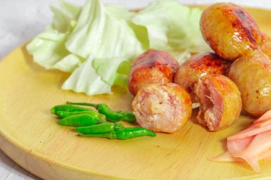 Isaan sosisi Tayland 'ın en ünlü yemeklerinden biridir, Isaan sosisi beyaz bir masada, kırmızı biber ve sebzelerle birlikte servis edilir..