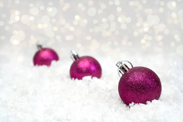 白色背景的圣诞装饰品 三颗发红的球躺在白雪上 在后台Bokeh 后续行动 — 图库照片