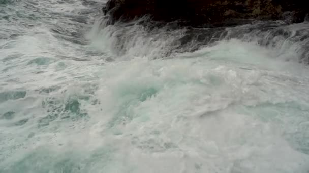 嵐の海と海岸の崖の印象的な非常に近いビュー 波は石に対して強力に衝突し 白い泡を上げ スプレーする 海の水が岩の上を転がって戻ってきます スローモーション撮影 — ストック動画