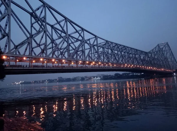 Lights illuminated at Howrah Bridge that reflects at river Ganga turn golden look mesmerizing in Kolkata. This is landmark of Kolkata which was build by British East India Railway Company in 1943. It carries 100000 vehicles and 150000 pedestrians.