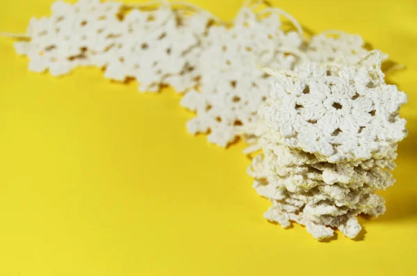 Een stapel van haak witte sneeuwvlokken op een gele achtergrond met een kopieerruimte — Stockfoto