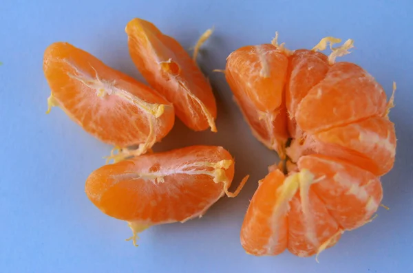 Três fatias de tangerina descascada fresca com meia vista de close-up de tangerina de cima do fundo azul — Fotografia de Stock