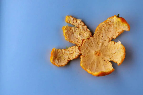 Descasque uma tangerina fresca em um fundo azul com espaço de cópia — Fotografia de Stock