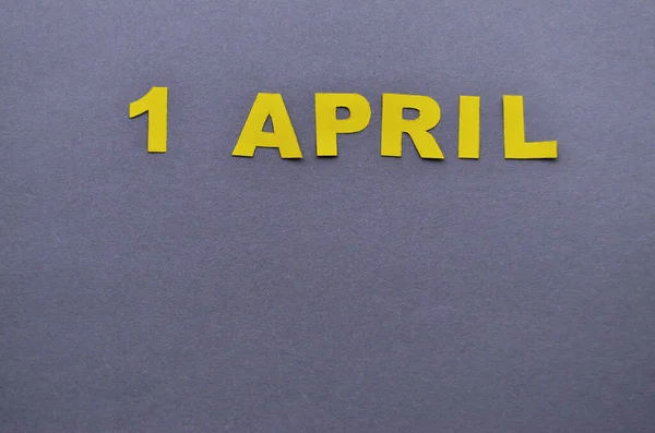 Дата 1 квітня викладається з паперових літер жовтого кольору на сірому фоні з пробілом для копіювання — стокове фото