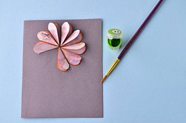 Adım adım fotoğraf çekerek bir çiçekle nasıl tebrik kartı yapılacağı öğretiliyor. Adım 10. Yeşil akrilik boya ve fırçayı hazırlayın.