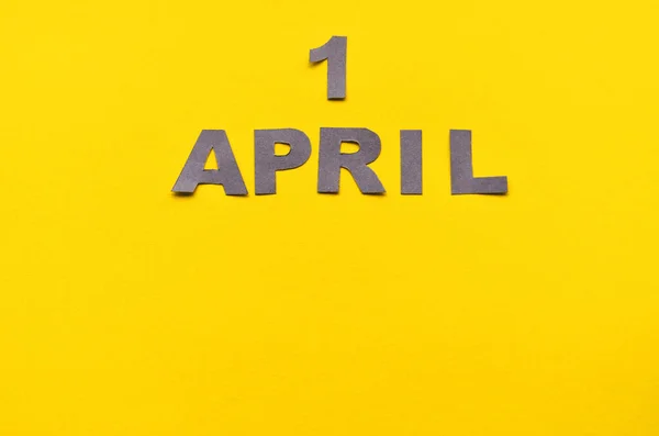 Inscrição 01 de abril de letras esculpidas de cinza em um fundo amarelo com espaço de cópia — Fotografia de Stock
