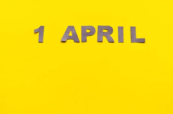 Inscription April 1 from carved letters of gray on a yellow background with copy space — Stock Photo, Image