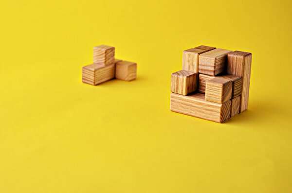 Логическая игра деревянная головоломка куба без одного элемента на желтом фоне с копировальным пространством. Решение логических проблем