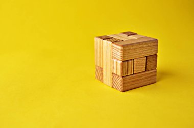 Mantıksal yapboz oyunu tahta küp bulmacası. Kopya alanı olan sarı bir arka planda toplanmış şekilde. Mantıklı problemler çözülüyor