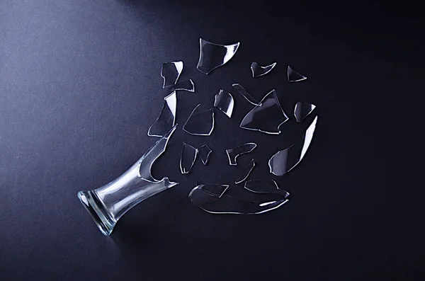 Broken glass vase with decomposed shards of glass on a black background