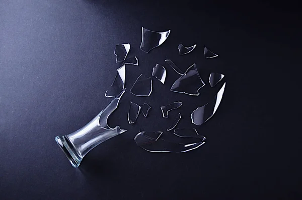 Gebroken glazen vaas met afgebroken glasscherven op een zwarte ondergrond Stockfoto