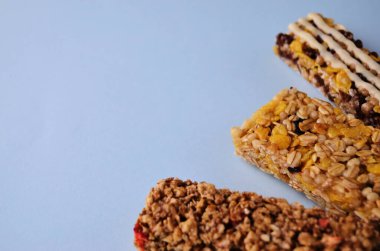 Sağ alt köşede üç çubuk granola fanı var. Fotokopi alanı olan mavi bir arka plan yakın plan.