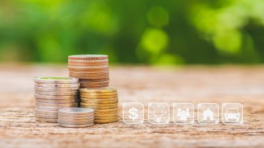 Ahşap masa üzerinde para tasarrufu simgesi olan bozuk paralar arka planda bulanık. Tasarruf ve yatırım kavramı.