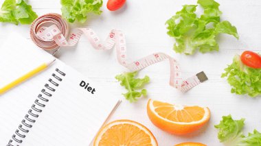 Meyveler, sebzeler ve bel bandı beyaz bir masaya yerleştirilir üst görüş diyeti ve sağlıklı konsept kilo verme günlüğü, kilo ve yiyecek alımınıza dikkat edin, kalori.