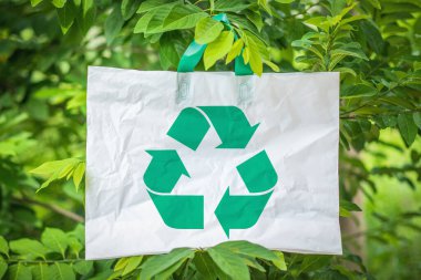 Beyaz plastik torba yeşil bokeh arka planını geri dönüştürüyor. Geri dönüşüm konsepti dünyayı temizlemeye yardımcı olur. ekolojik kavram