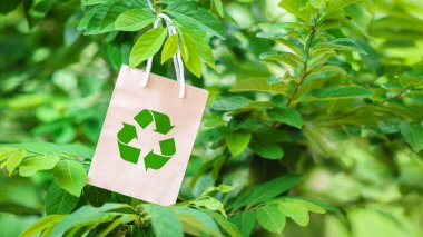 Geri dönüşüm vaadiyle dolu kağıt torba, yeşil bokeh arka plan. Geri dönüşüm konsepti dünyayı temizlemeye yardımcı olur. ekolojik kavram.