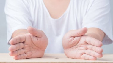 Two lonely hands on a wooden table in a protective look. concept of safety insurance.