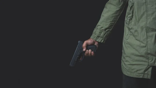 Elinde siyah arka planda, dikiz aynasından bir silah tutan bir adam. Elinde tabanca olan bir adam hedefine nişan alır..