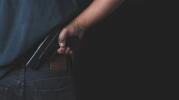 黒い背景の男が銃を手に持っていた 銃を持った男が標的を狙ってる — ストック写真