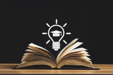 Siyah arkaplanda izole edilmiş ahşap masa üzerinde orta sayfa ve mezuniyet kapağı sembolünü aç.