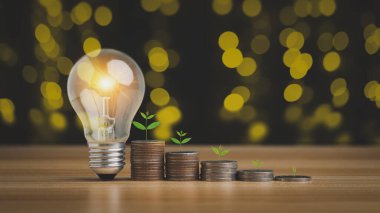 Bozuk paralar ampulle birlikte bir yığın içinde büyür. Para geliri kavramından tasarruf etmek için enerji ve para fikri.