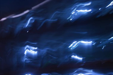 Karanlık bir arka planda ışık ya da elektriğe benzeyen mavi ışık çizgileriyle enerjik ve soyut bir arka plan..