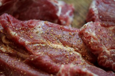 Üzerine baharat ve biber serpiştirilmiş taze et biftekleri. Pişmemiş domuz boynu ya da sığır eti dokusu arka planı.