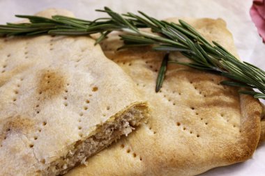 Ev yapımı rustik et turtası ya da taze biberiye filizi ile süslenmiş Focaccia ekmeği. Pişmiş lezzetli hamur işi dokusu.