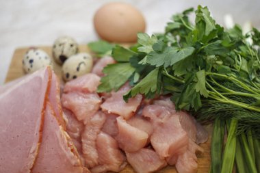 Dilimlenmiş jambon ve taze sebzeli çiğ tavuk fileto parçalarını kapatın. Salata için et malzemeleri.