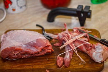 Çiğ et parçası ve tahta kesme tahtasındaki kemikler bıçak ve bileyiciyle. Ev mutfağında et kesme işlemi.