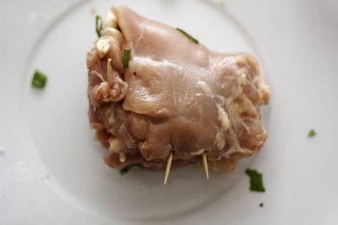 Peynirle doldurulmuş çiğ tavuk eti ve ahşap kürdanla güvence altına alınmış otlar. Yarı bitmiş ürün pişirmeye hazır..