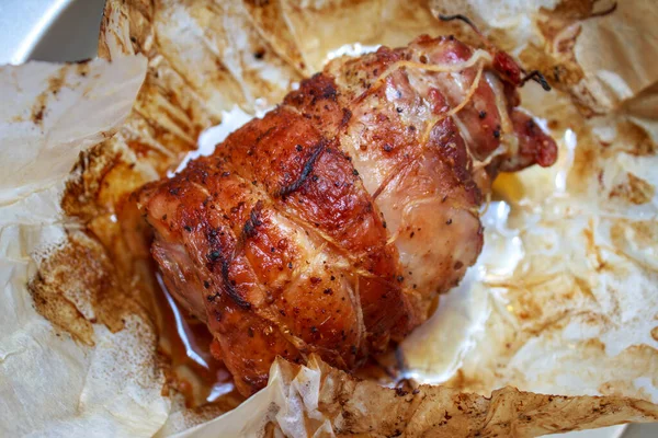 İştah açıcı kavrulmuş et rulosu, üzerinde altın kabuk ve fırın kağıdı var. Ev yapımı domuz eti tabağının üst görüntüsü..