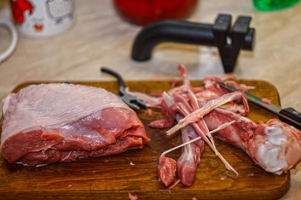 Çiğ et parçası ve tahta kesme tahtasındaki kemikler bıçak ve bileyiciyle. Ev mutfağında et kesme işlemi.