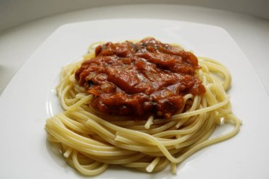Beyaz tabakta kırmızı domates soslu ev yapımı spagetti makarna. Klasik İtalyan yemeği..
