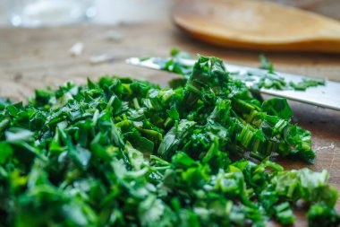 Taze doğranmış yeşil ıspanak ya da bir bıçakla tahta kesme tahtasındaki bitkiler. Sağlıklı sebze içeriği.