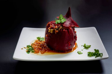 Siyah arka planda beyaz bir tabakta servis edilen doldurulmuş pancar kökü. Gurme sebze yemeği..