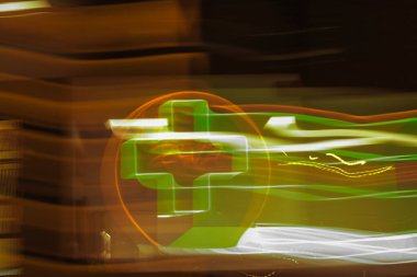 Parlayan yeşil bir eczane ışığı altında soyut hareket bulanıklığı. Geceleri sağlık ve sağlık acil durum kavramı.