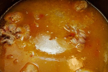 Yağ kaplı pirinç ve kazanda köfte ile kaynar su. Pilavın sıvı aşaması pişiriliyor.