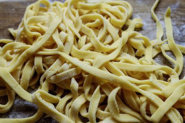 Un kaplı ahşap tahtanın üzerinde yuvalara dizilmiş taze çiğ yumurtalı makarna. Ev yapımı İtalyan yemekleri..