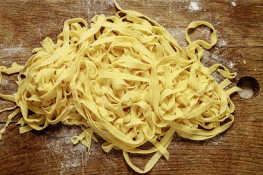 Tahta masaya saçılmış çiğ yumurtalı makarna dokusu. Pişmemiş ev yapımı spagetti arka planı.