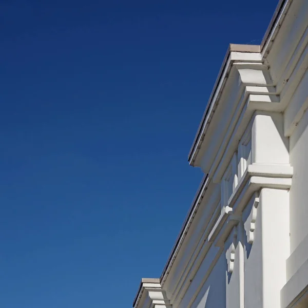 Açık Mavi Gökyüzünün Altındaki Beyaz Bir Binanın Üst Kısmının Düşük — Stok fotoğraf