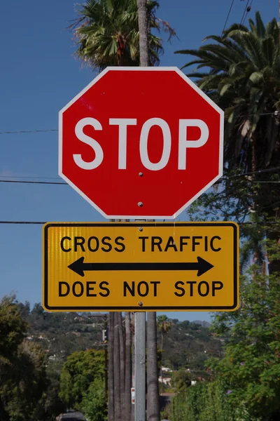 City red traffic STOP sign with additional yellow sign CROSS TRAFFIC DOES NOT STOP