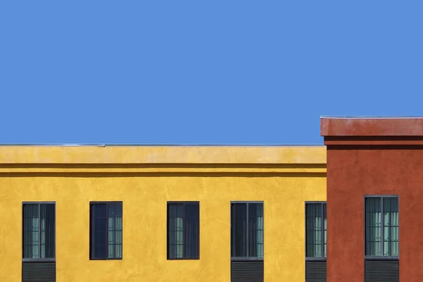 大きな赤と黄色の建物と青空の屋根のセクション — ストック写真