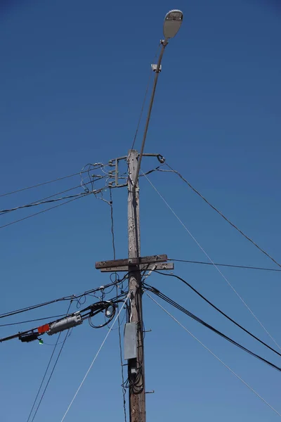 蓝天下带有路灯和电线的配电塔的低角度视图 — 图库照片