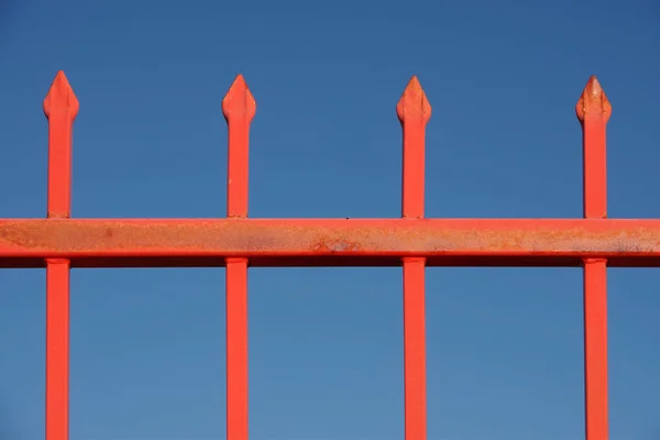 红色橙色金属栅栏的一部分 蓝天后面的特写 — 图库照片