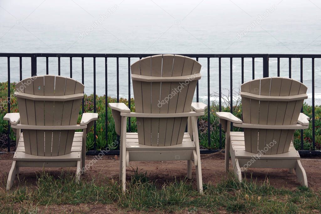 Adirondack chairs lined up outside on a foggy evening on the central California coast