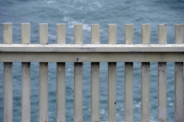 经风吹日晒的白色木制警戒线围栏的近景 后面可见大海 — 图库照片