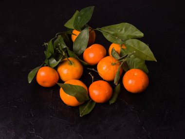 Siyah arka planda yaprakları olan mandalinalar. Çin tatlı mandalinaları