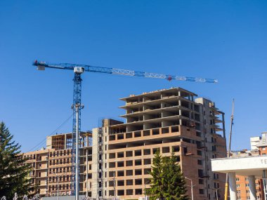 İnşaat kulesi vinci büyük bir bina inşa ediyor. Yaz güneşli bir gün