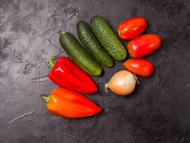 Siyah arka planda sebzeler. Vejetaryen yemeği için gerekli malzemeler. Kırmızı biber, soğan, sarımsak ve salatalık. Yukarıdan görüntüle